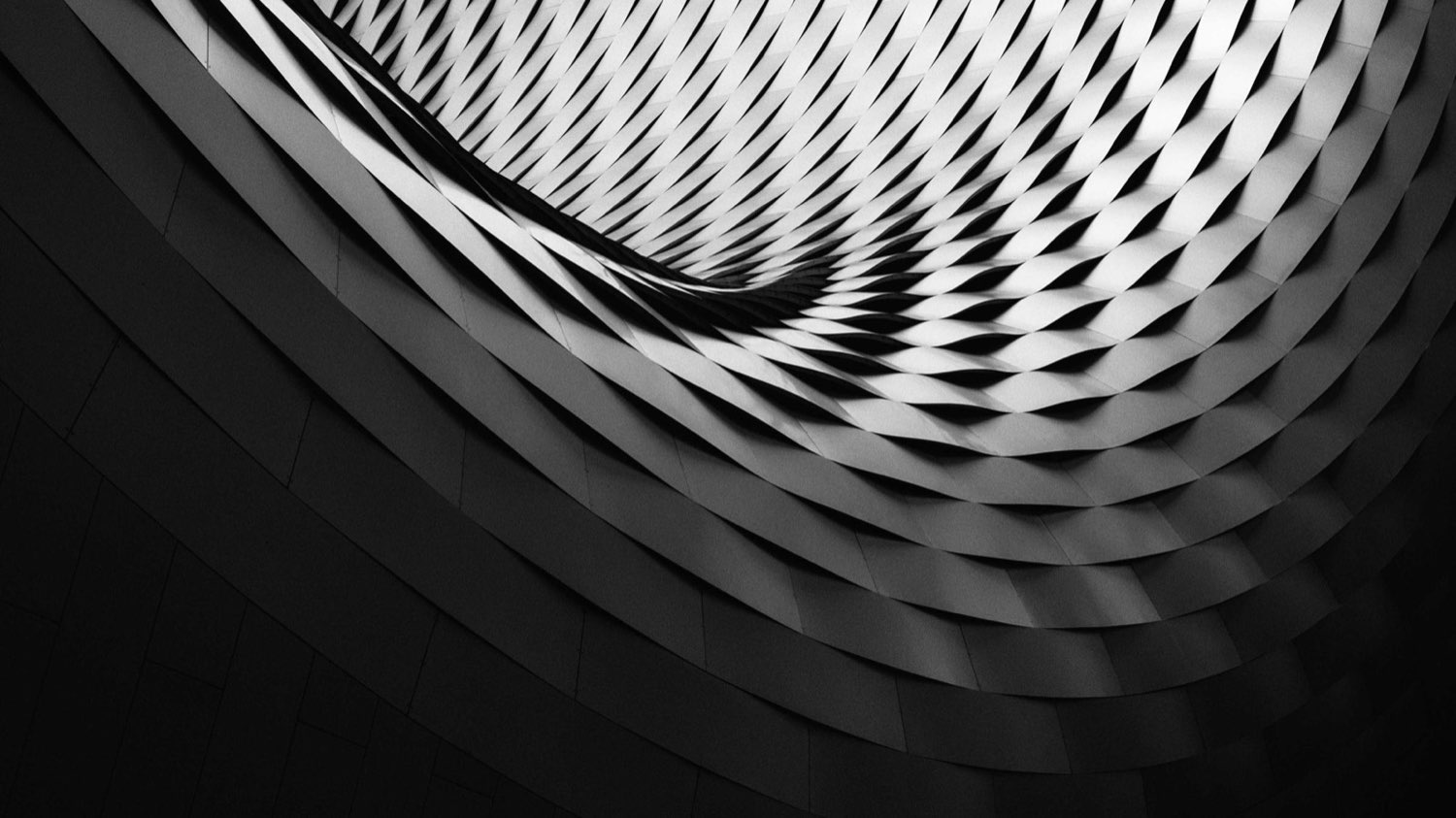 A curved, latticed building facade: repeating panels forming one precise structure.